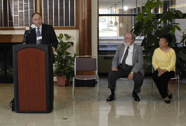 President Al Goldfarb, at podium, announces the largest planned gift in the University's history by Drs. Norman and Carmelita Teeter, seated.